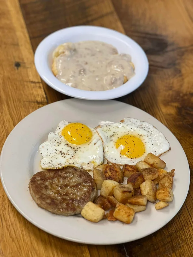 Fried eggs, sausage, hash browns, and biscuits with gravy.
