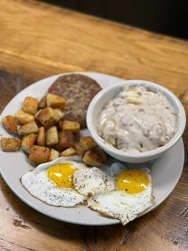 Two sausage patties, eggs, hash browns, and biscuits with gravy.