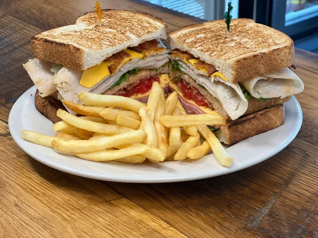 Club sandwich with turkey, ham, bacon, cheese, lettuce and tomato, with fries.