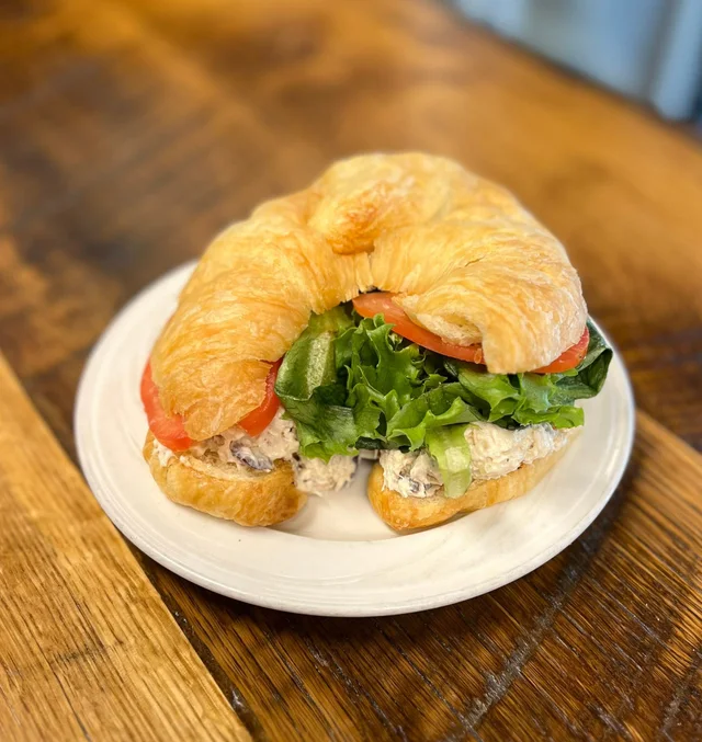 Homemade chicken salad with red grapes in a croissant with lettuce and tomato.