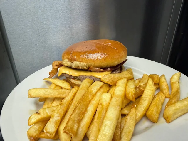Bacon cheeseburger on a bun with fries.