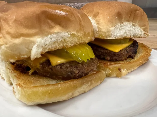 Two goetta sliders with cheese and pickles.