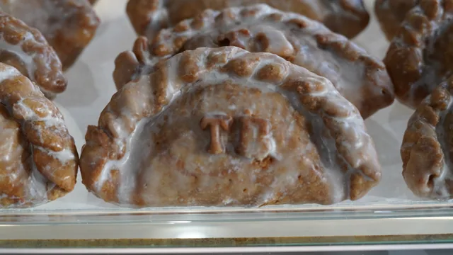 A row of folded pastries finished with a shiny glaze in the bakery case.