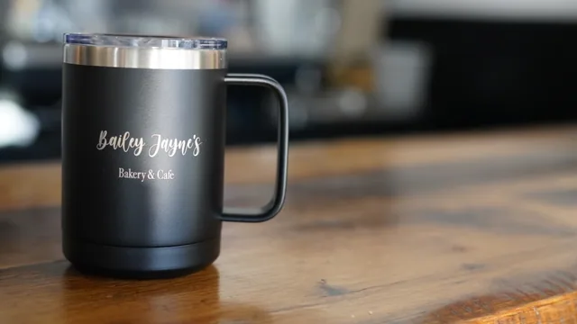 A black Bailey Jayne’s Bakery & Cafe insulated mug on a wooden counter.