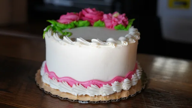 A white cake topped with pink icing roses and finished with a pink border.