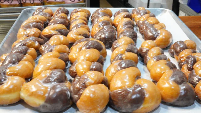 A full tray of twisted donuts with alternating golden and dark sections under a glaze.