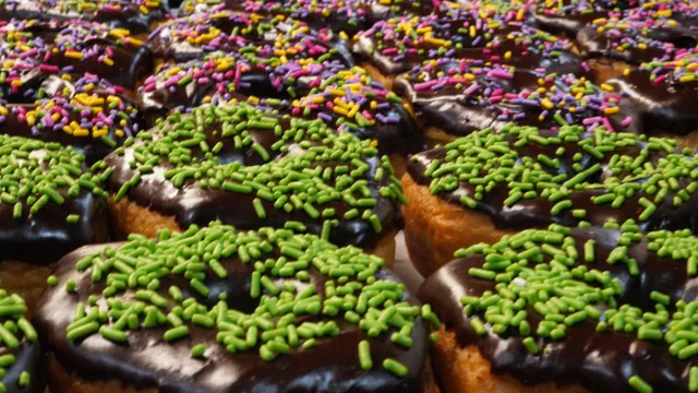 Chocolate-topped donuts covered in bright green, pink and yellow sprinkles.