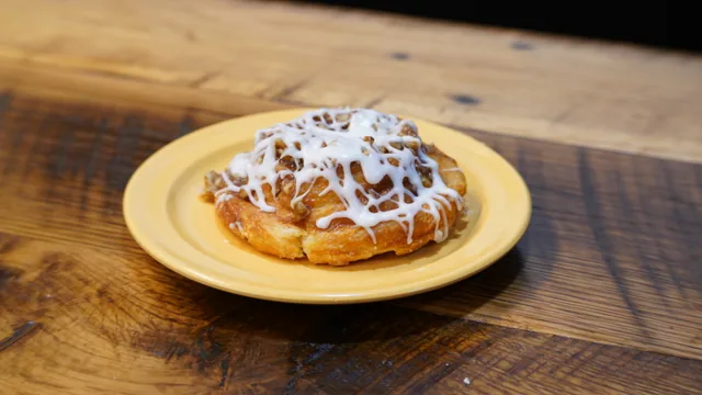 A spiral pastry with a crumb topping and white icing drizzle.