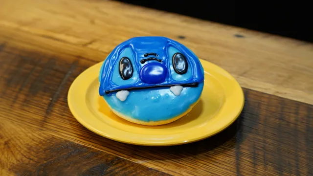 A round donut with bright blue icing and a playful character face.