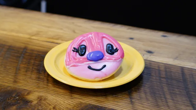 A round pink-iced donut decorated with a playful character face.