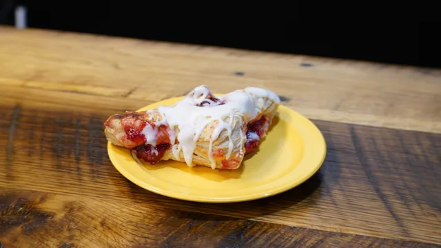 A twisted pastry with visible red filling and white icing drizzle.
