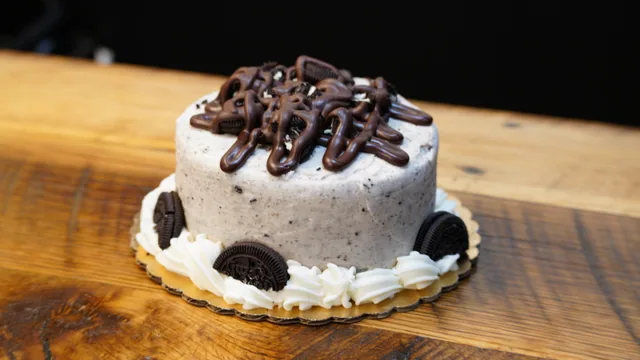 A crumb-speckled cake topped with sandwich cookies and dark icing drizzle.