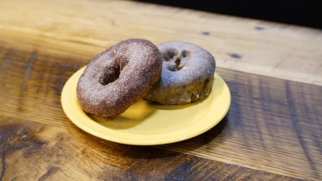 Two ring donuts, one coated in fine sugar and one with a thin glaze.