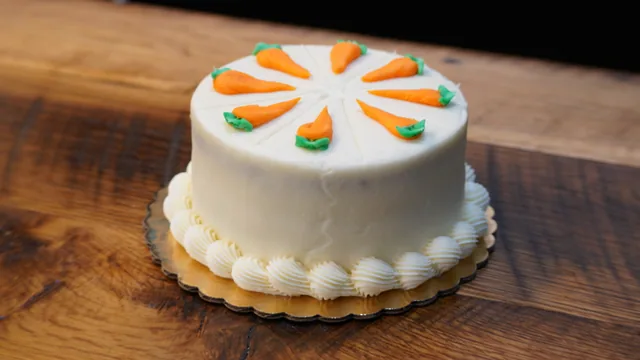 A white round cake decorated with a ring of orange icing carrots.